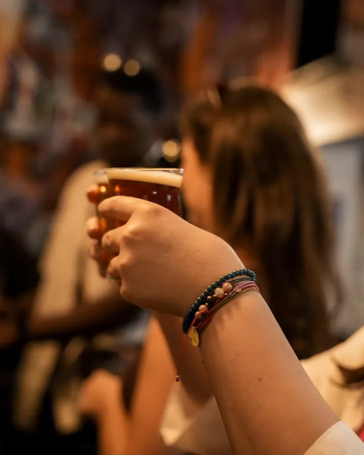 A guest raising a glass of beer at the bar